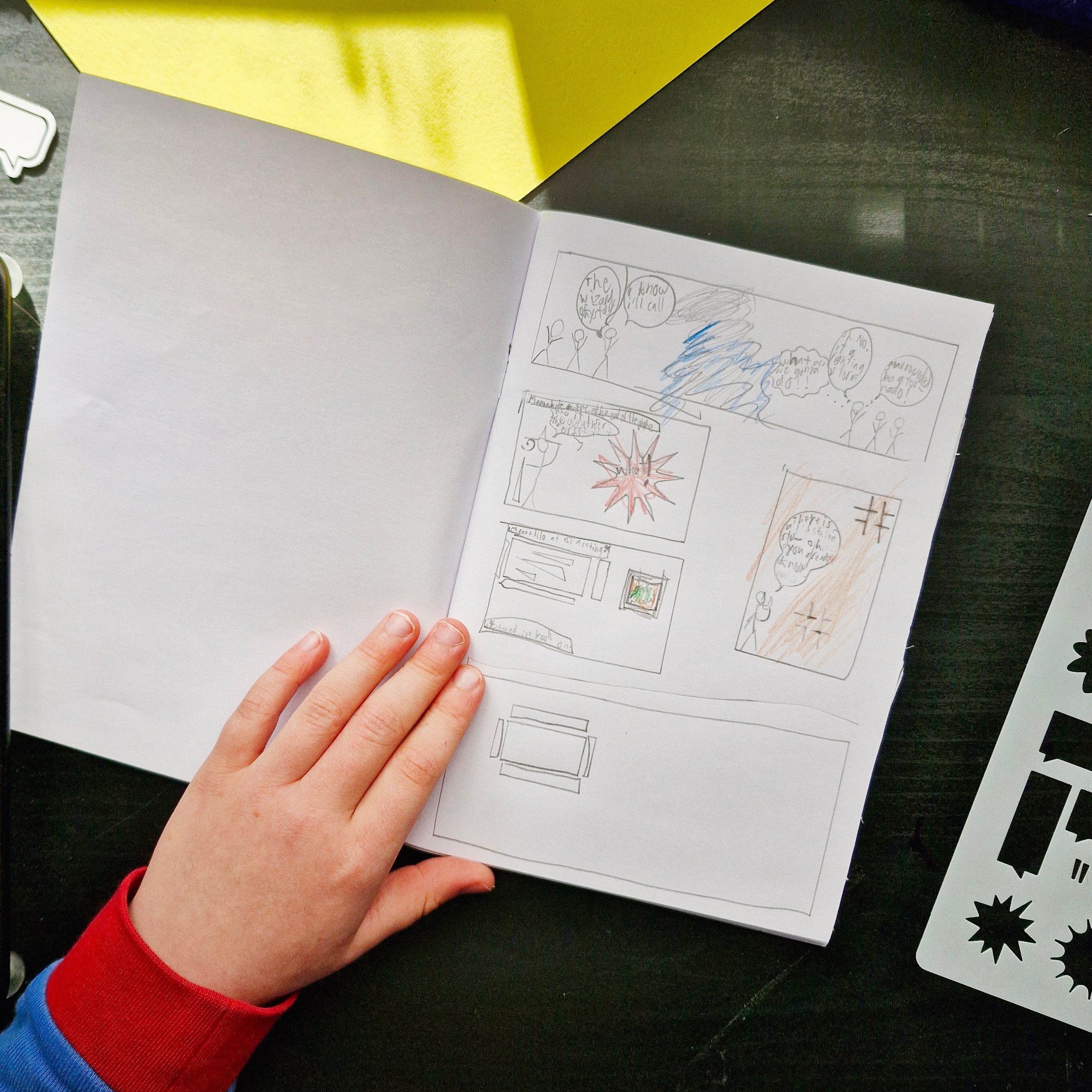 Open notebook with hand-drawn comic strip on a dark surface