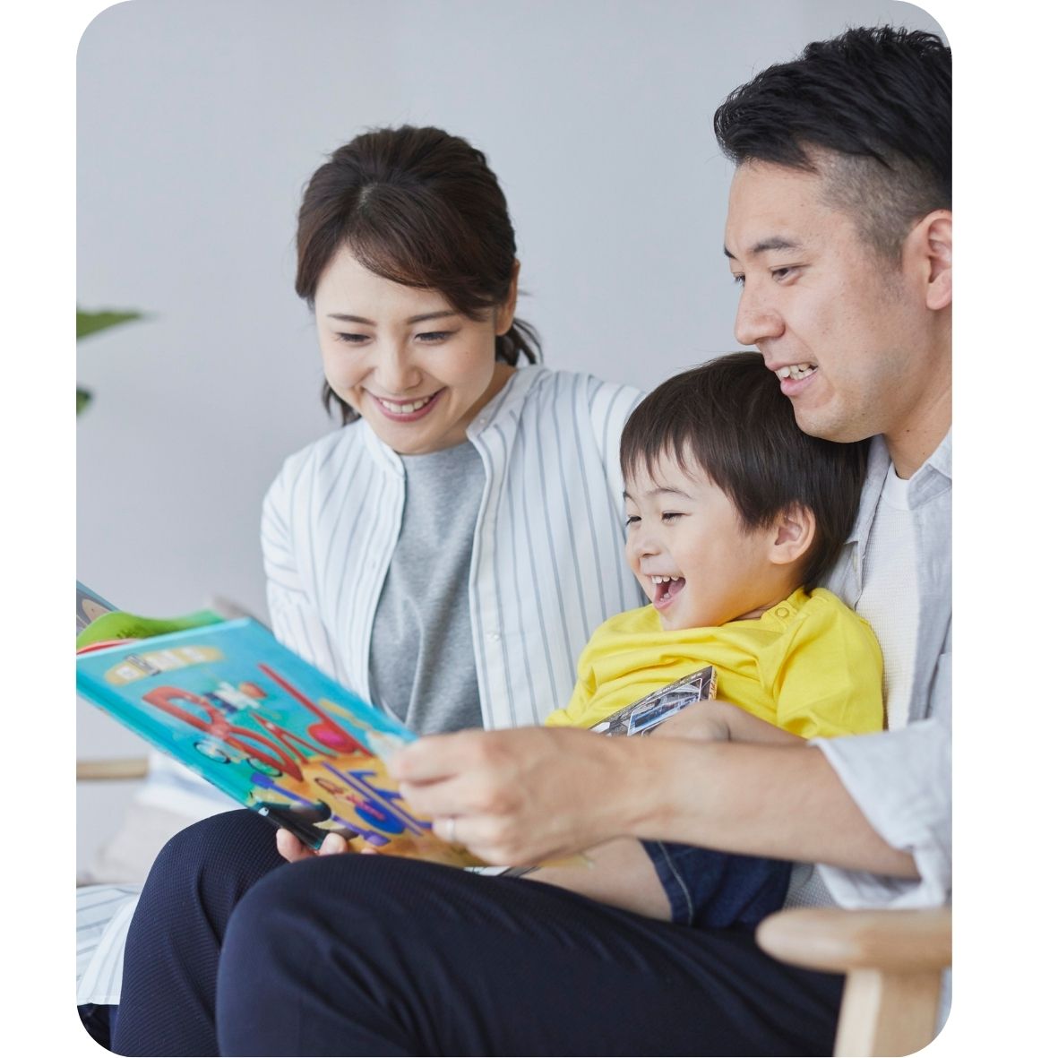 Asian family reading a book together, smiling and happy