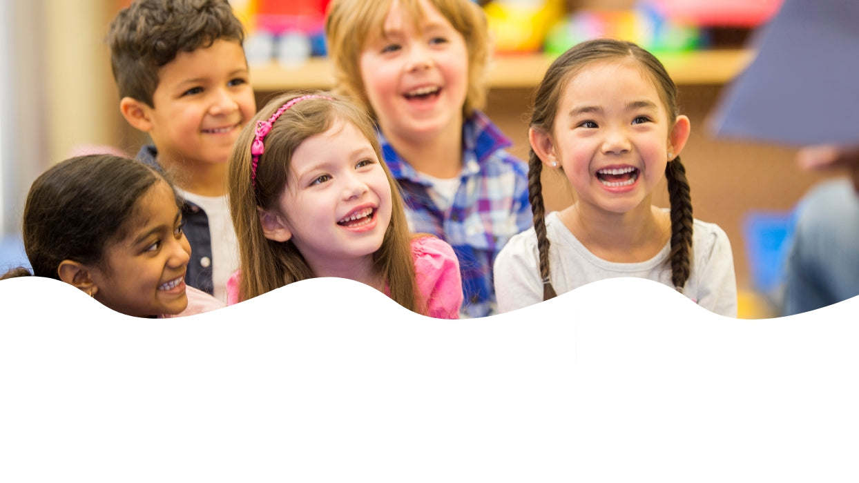 Children sitting together, smiling, with a colorful classroom background